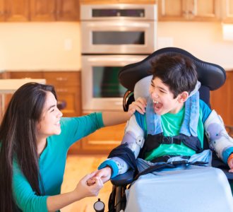 boy in wheelchair laughing with teen sister in kitchen